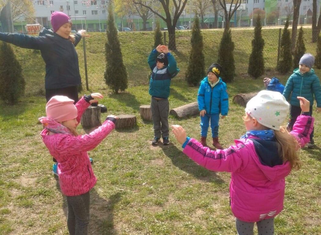 Dzieci na trawie wykonują ćwiczenia sportowe