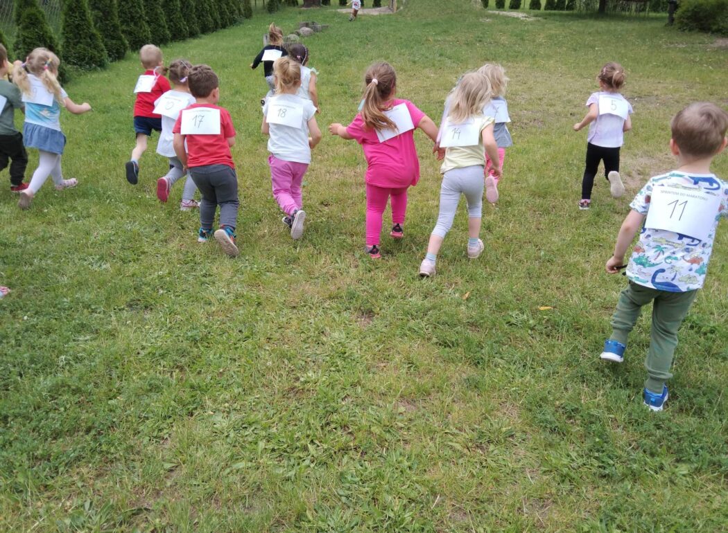 dzieci na biegną po trawie