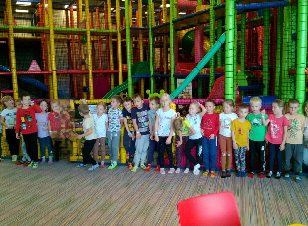 dzieci stoją w rzędzie przed rusztowaniem na placu zabaw