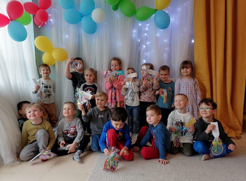 uśmiechniete dzieci na tle ściany udekorowanej kolorowymi balonami